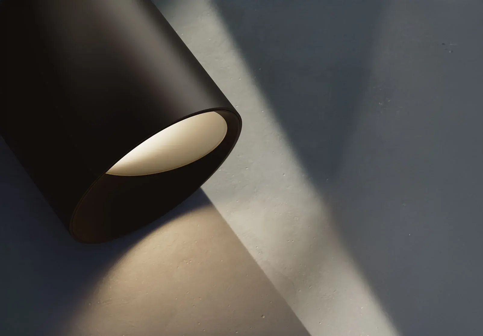Black DMF cylinder on a wall casting a soft beam