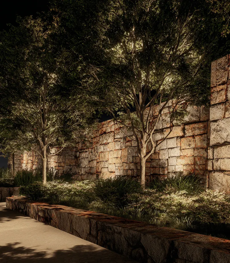 Stone garden wall washed with light behind young trees